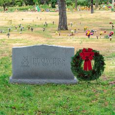 a wreath is placed next to a grave in the middle of a grassy area with many people around it