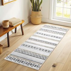 a wooden bench sitting next to a white rug on top of a hard wood floor