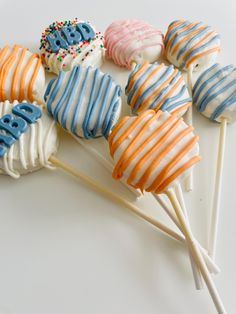 a bunch of cake pops sitting on top of a white table next to each other