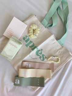 the contents of a shopping bag laid out on top of a white bed with green straps