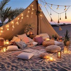 a bed covered in pillows and lights on the beach