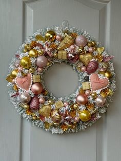 a christmas wreath hanging on the front door with ornaments around it and an ornament