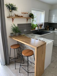 two stools are sitting at the counter in this modern kitchen with open shelving