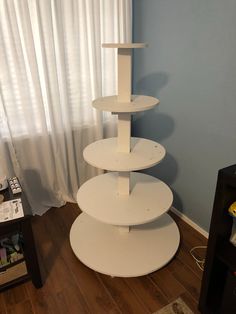 a tall white shelf sitting on top of a hard wood floor next to a window