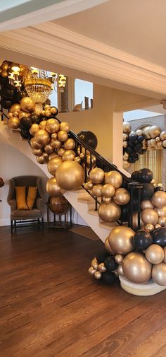 a staircase decorated with gold and black balloons