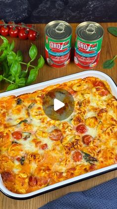 a casserole dish with tomatoes, spinach and cheese on the side next to two cans of soda