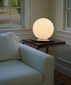 a white couch sitting next to a table with a lamp on it's side