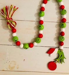 a necklace made out of green and red beads with smiling faces on it, hanging from a string