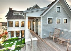 a wooden bench sitting on top of a wooden deck next to a white house with windows