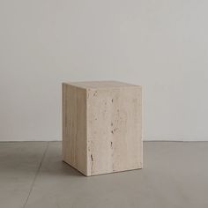 a small block of concrete sitting on top of a cement floor next to a white wall