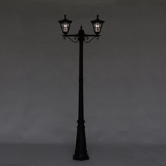 an old fashioned street lamp with two lights on it's sides against a gray background