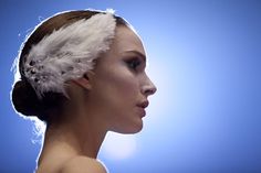 a woman with white feathers on her head and hair comb in her hair, against a blue background