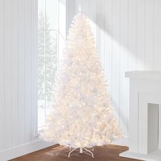 a white christmas tree in a room with wood flooring and walls, all lit up