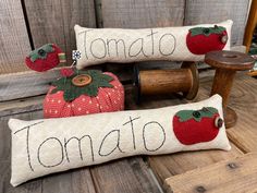 two decorative pillows sitting on top of a wooden bench