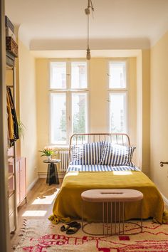 a bedroom with yellow walls and a bed in the corner, next to a window