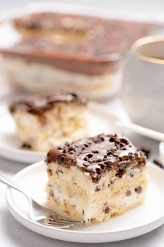 a piece of cake sitting on top of a white plate next to a cup of coffee