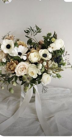 a bouquet of flowers on a bed with a white ribbon tied around the bottom of it