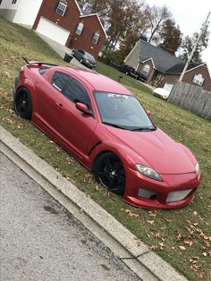 a red sports car parked on the side of a road in front of a house