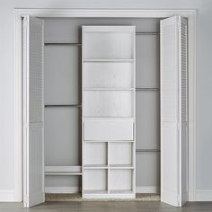 an open closet with white shelves and closed doors on both sides, against a gray wall