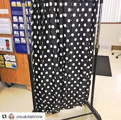 a black and white polka dot shower curtain in a room with an open bookcase