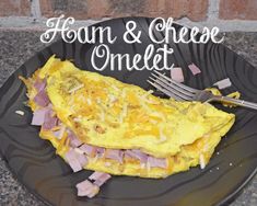 an omelet with ham and cheese is on a black plate