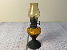 an old fashioned oil lamp sitting on top of a wooden table