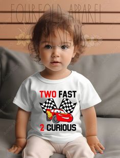 a toddler sitting on top of a couch wearing a t - shirt that says two fast 2 curious