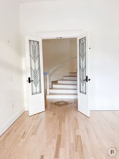 an empty room with white walls and wooden floors, two doors leading to the second floor