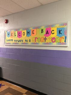 a welcome back sign hanging on the wall in a school hallway with checkered flooring