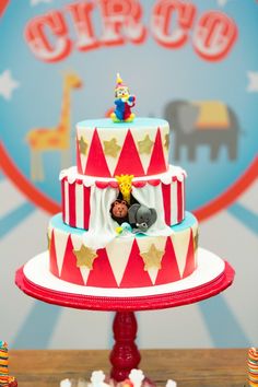 a circus themed birthday cake with clowns on the top and circus decorations around it