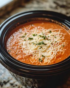 a close up of a bowl of soup with parmesan cheese and herbs on top