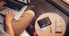 a man is sitting on the floor with his laptop and money in front of him