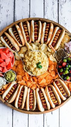 a platter filled with hot dogs, vegetables and dips