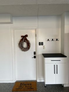 a door with a wreath hanging on the side of it next to a white cabinet