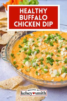 healthy buffalo chicken dip recipe in a glass bowl with crackers and vegetables on the side