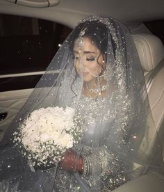 a woman in a car wearing a veil and holding a bouquet of white flowers on her wedding day