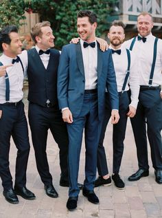 a group of men standing next to each other wearing suits and bow ties on their heads