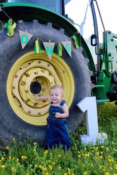 a little boy standing in front of a tractor