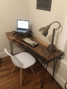 a laptop computer sitting on top of a wooden desk next to a white chair and lamp