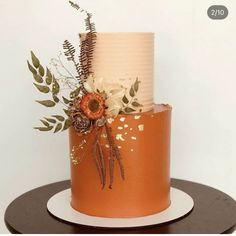 a three tiered cake decorated with flowers and leaves