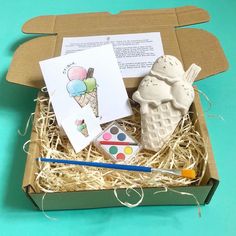 an ice cream sundae in a cardboard box with watercolors and paintbrushes