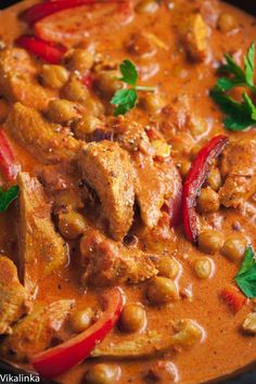 chicken curry with red peppers and chickpeas in a black bowl, garnished with parsley