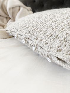 a white crocheted pillow sitting on top of a bed