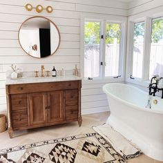 a bathroom with a sink, mirror and bathtub next to two windows in it