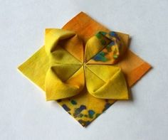 an origami flower sitting on top of a yellow napkin