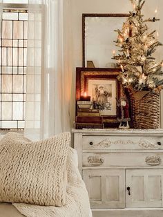 a living room with a white couch and a christmas tree on top of a dresser