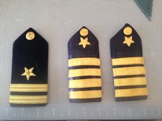 three small black and yellow tags with gold stars on them sitting next to a ruler