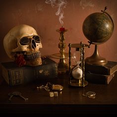 a table topped with books and a skull next to an hour glass on top of it