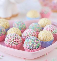 there are many colorful cupcakes on the pink plate with sprinkles