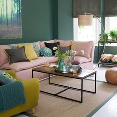 a living room with green walls and pink couches in the corner, along with other furniture